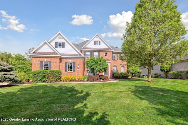 colonial-style house featuring brick siding, a front lawn, a standing seam roof, and metal roof