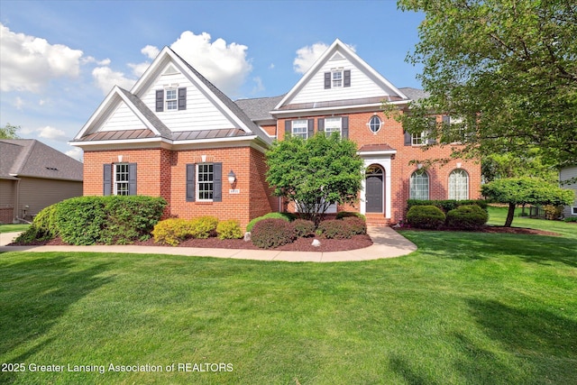georgian-style home with a standing seam roof, brick siding, a front yard, and metal roof