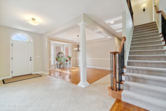entryway featuring light tile patterned floors, stairway, baseboards, a chandelier, and decorative columns