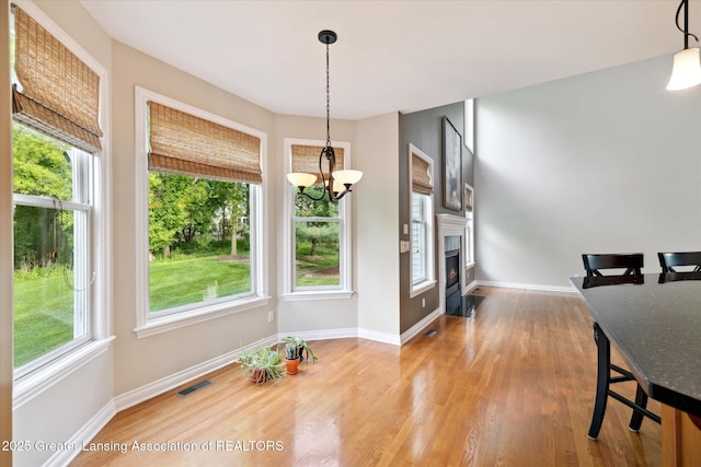 dining room with plenty of natural light, wood finished floors, a chandelier, and baseboards