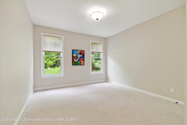 empty room featuring carpet flooring, plenty of natural light, and baseboards