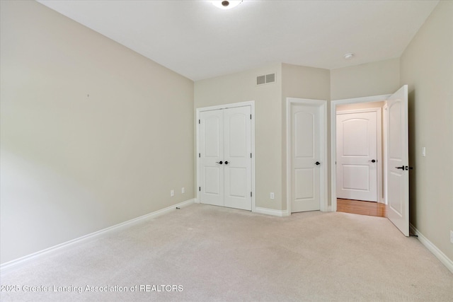 unfurnished bedroom featuring light carpet, baseboards, and a closet