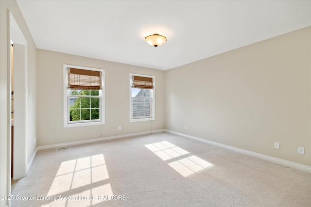 spare room with light colored carpet and baseboards