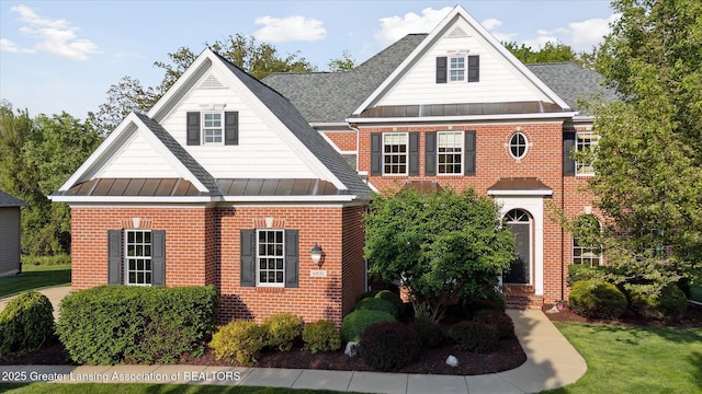 view of front of property featuring brick siding, a standing seam roof, and roof with shingles