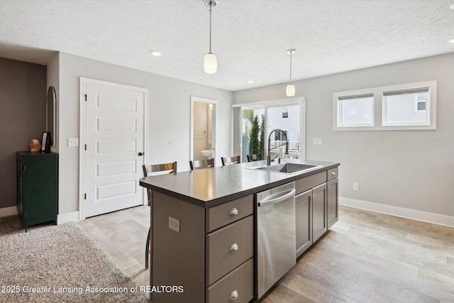 3842 Fossum Ln, Okemos, MI 48864 - kitchen with stainless steel dishwasher, a sink, dark countertops, a center island with sink, and decorative light fixtures