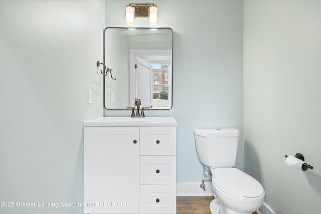 1229 W Saginaw St, Lansing, MI 48915 - half bathroom with baseboards, toilet, vanity, and wood finished floors