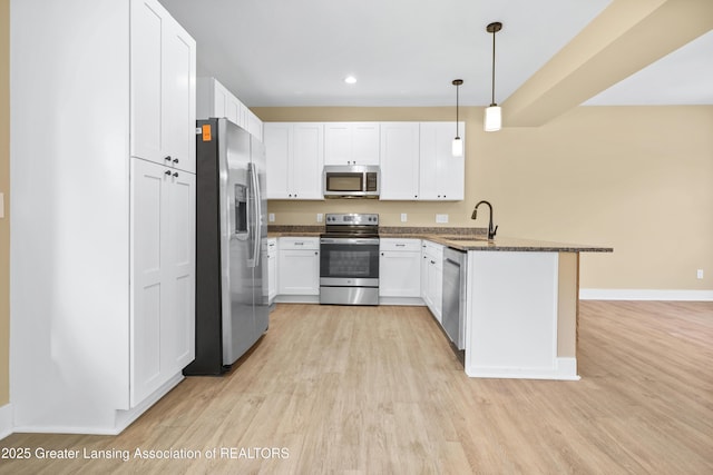 1229 W Saginaw St, Lansing, MI 48915 - kitchen with stainless steel appliances, a peninsula, a sink, light wood-style floors, and recessed lighting