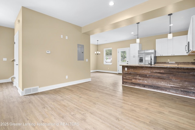 1229 W Saginaw St, Lansing, MI 48915 - unfurnished living room with light wood-style flooring, electric panel, baseboards, recessed lighting, and a chandelier