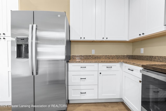 1229 W Saginaw St, Lansing, MI 48915 - kitchen featuring stainless steel fridge, white cabinets, stove, dark stone countertops, and wood finished floors