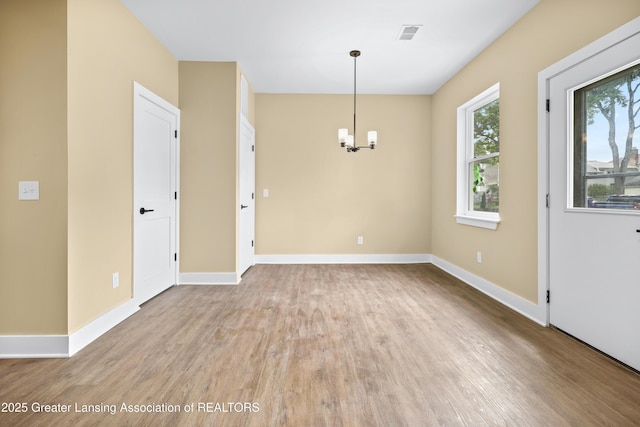 1229 W Saginaw St, Lansing, MI 48915 - empty room featuring light wood finished floors, baseboards, and a chandelier