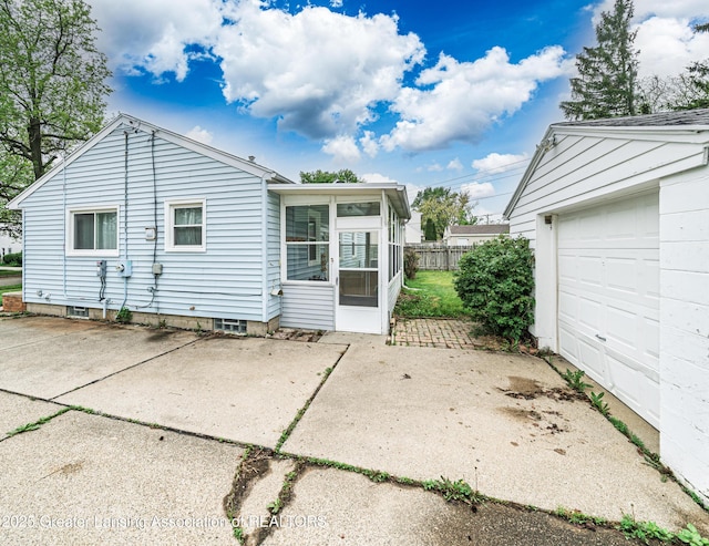 2018 Cooper Ave, Lansing, MI 48910 - back of property with a garage, a sunroom, fence, and driveway