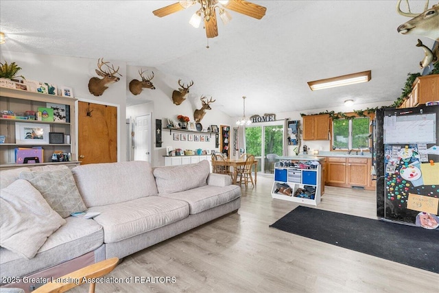 5669 Elm Rd, Olivet, MI 49076 - living area with a ceiling fan, light wood finished floors, vaulted ceiling, and a chandelier