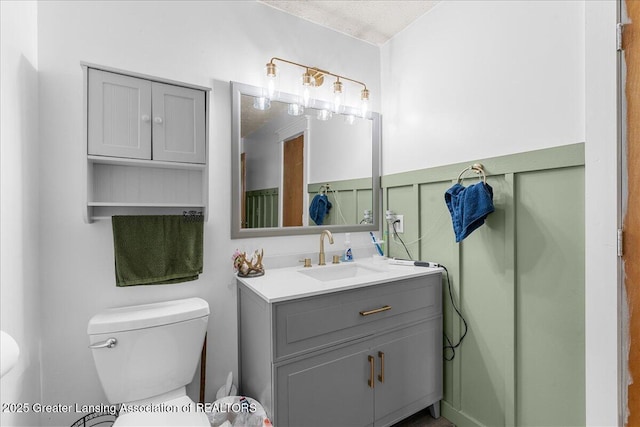 5669 Elm Rd, Olivet, MI 49076 - half bath featuring toilet, vanity, and a wainscoted wall