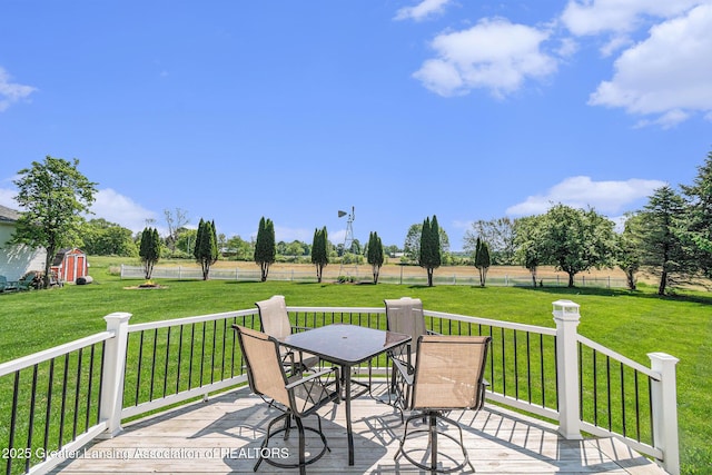 985 Ives Rd, Mason, MI 48854 - deck with outdoor dining space, a lawn, a storage unit, and an outbuilding