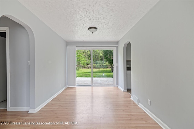 2468 Lansing Rd, Charlotte, MI 48813 - spare room with light wood-type flooring, baseboards, and a textured ceiling