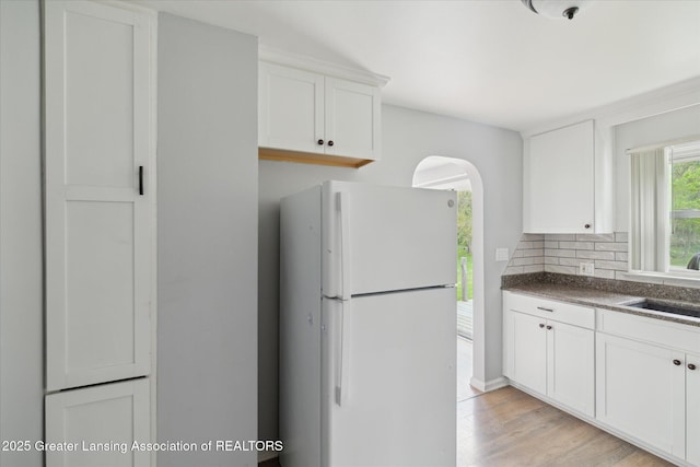 2468 Lansing Rd, Charlotte, MI 48813 - kitchen with freestanding refrigerator, a sink, arched walkways, white cabinetry, and dark countertops