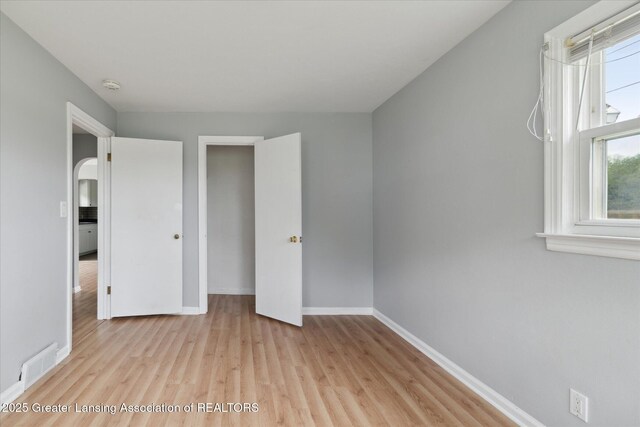 2468 Lansing Rd, Charlotte, MI 48813 - unfurnished bedroom with wood finished floors, baseboards, and arched walkways
