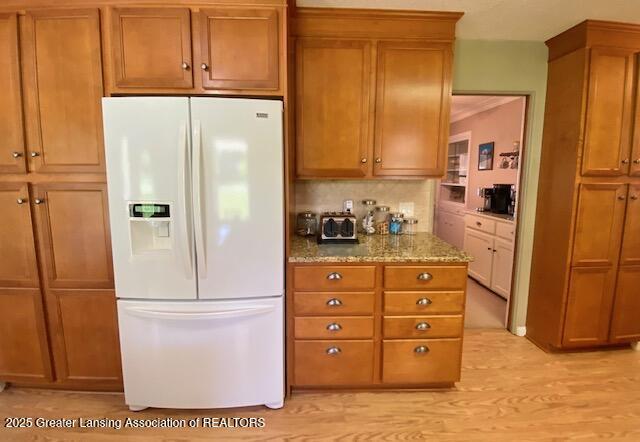 15426 Boichot Rd, Lansing, MI 48906 - kitchen with white refrigerator with ice dispenser, brown cabinets, and light stone countertops