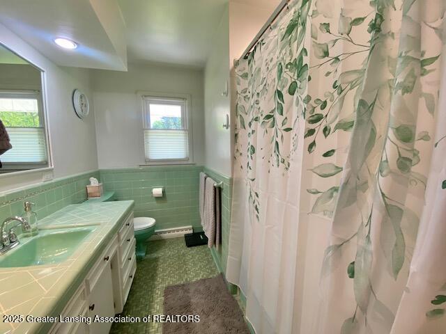 15426 Boichot Rd, Lansing, MI 48906 - full bathroom featuring tile walls, vanity, toilet, a wainscoted wall, and a shower with curtain
