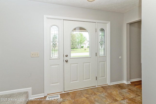 3979 Dayspring Ct, Okemos, MI 48864 - entryway with baseboards, stone finish floors, and a textured ceiling