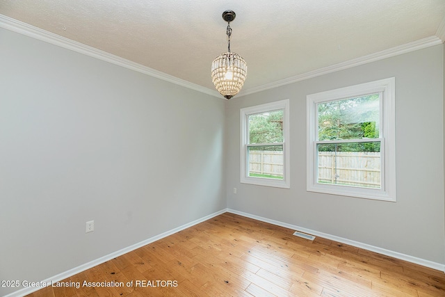 3979 Dayspring Ct, Okemos, MI 48864 - empty room featuring ornamental molding, light wood-style floors, baseboards, and a chandelier