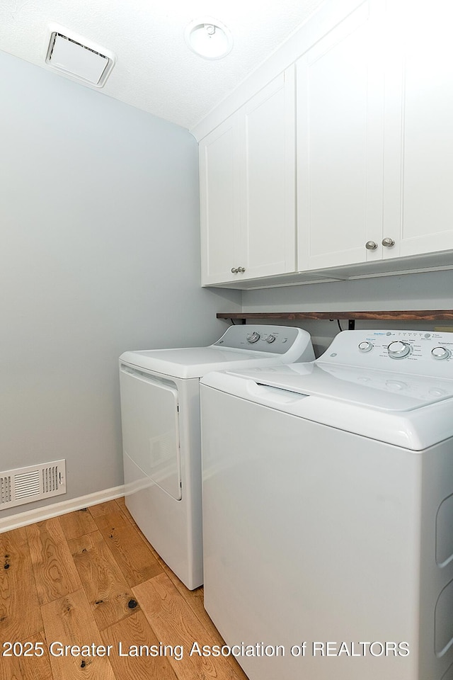 3979 Dayspring Ct, Okemos, MI 48864 - laundry room featuring cabinet space, washer and dryer, and light wood-style floors