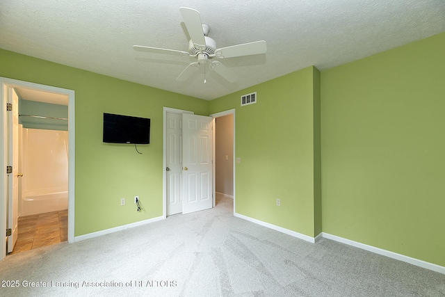 3979 Dayspring Ct, Okemos, MI 48864 - unfurnished bedroom with carpet, a textured ceiling, connected bathroom, baseboards, and a ceiling fan