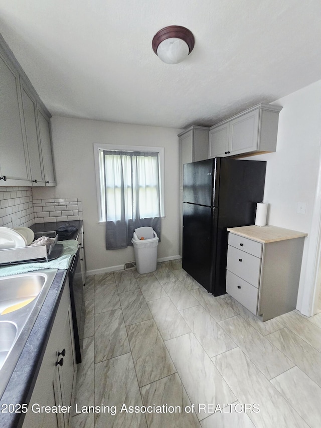 1427 Sheldon St, Lansing, MI 48906 - kitchen featuring light marble finish flooring, freestanding refrigerator, baseboards, gray cabinets, and backsplash