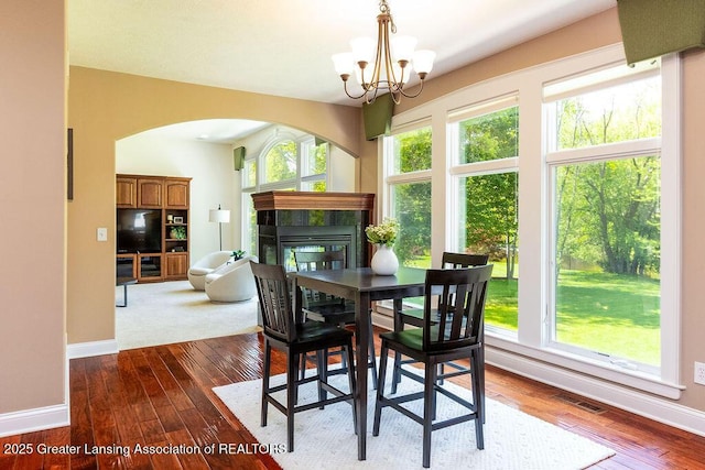 4655 Dimond Way, Dimondale, MI 48821 - dining space with a chandelier, baseboards, dark wood finished floors, and a tiled fireplace
