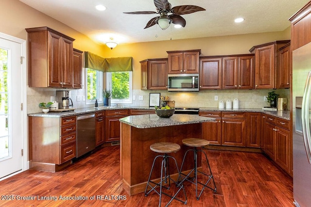 4655 Dimond Way, Dimondale, MI 48821 - kitchen featuring stainless steel appliances, dark wood finished floors, decorative backsplash, a center island, and a ceiling fan