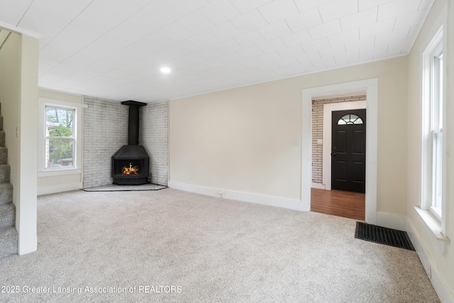 828 Backus St, Jackson, MI 49202 - unfurnished living room with carpet floors, a wood stove, and baseboards