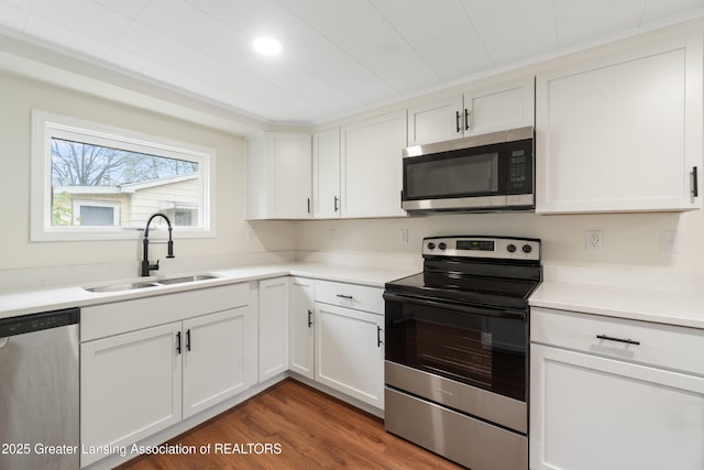 828 Backus St, Jackson, MI 49202 - kitchen with appliances with stainless steel finishes, a sink, white cabinetry, and wood finished floors