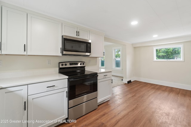 828 Backus St, Jackson, MI 49202 - kitchen featuring stainless steel appliances, light wood-style flooring, light countertops, white cabinetry, and baseboards