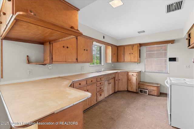 224 S Grace St, Lansing, MI 48917 - kitchen featuring washing machine and clothes dryer, a peninsula, light countertops, baseboards, and light flooring