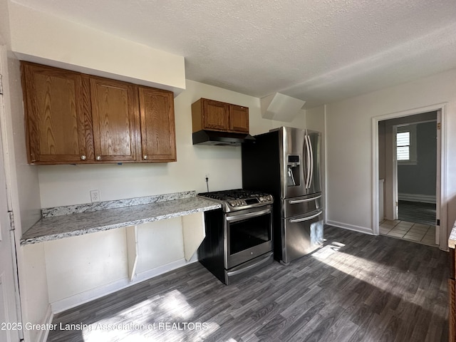 312 Jones St, Lansing, MI 48912 - kitchen with appliances with stainless steel finishes, under cabinet range hood, dark wood finished floors, brown cabinets, and baseboards