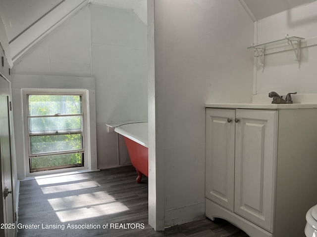 312 Jones St, Lansing, MI 48912 - bathroom featuring vanity, a soaking tub, wood finished floors, toilet, and lofted ceiling
