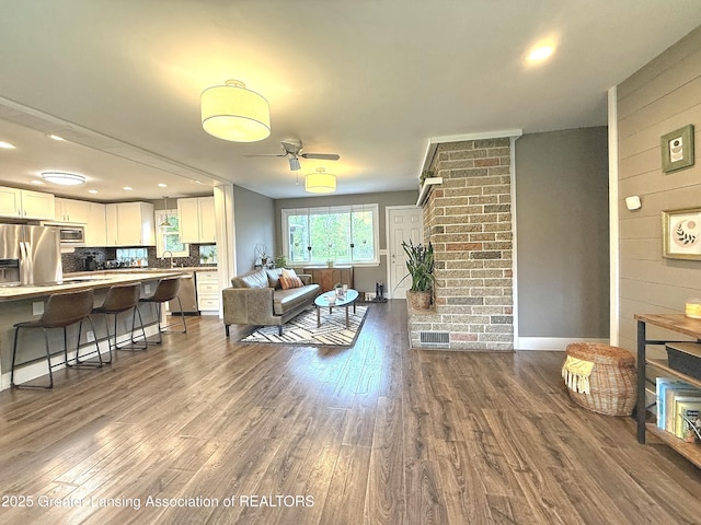 2215 Haslett Rd, East Lansing, MI 48823 - living room with dark wood-type flooring, ceiling fan, wood walls, baseboards, and recessed lighting