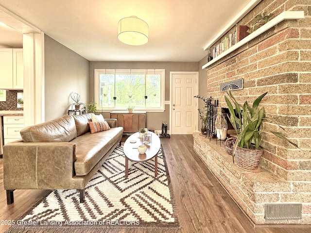 2215 Haslett Rd, East Lansing, MI 48823 - living room featuring wood finished floors, a brick fireplace, and brick wall