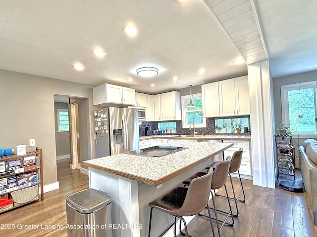 2215 Haslett Rd, East Lansing, MI 48823 - kitchen featuring appliances with stainless steel finishes, dark wood-type flooring, healthy amount of natural light, a kitchen bar, and recessed lighting