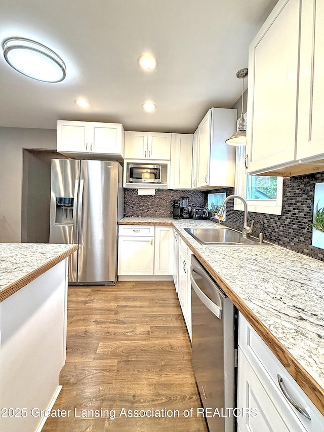 2215 Haslett Rd, East Lansing, MI 48823 - kitchen featuring stainless steel appliances, a sink, white cabinetry, decorative backsplash, and recessed lighting