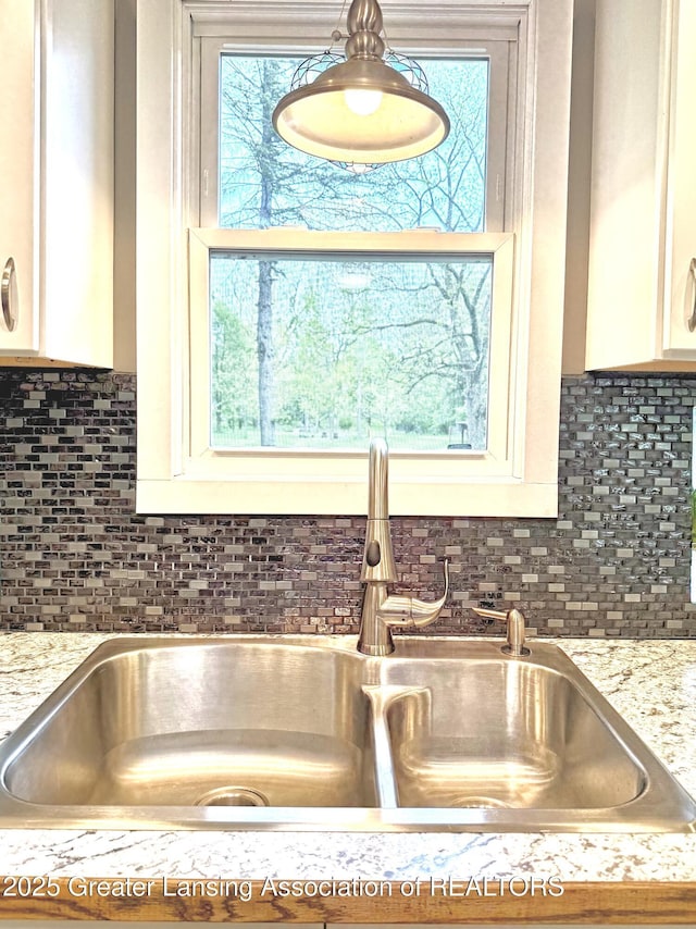 2215 Haslett Rd, East Lansing, MI 48823 - kitchen view of a sink, white cabinets, and decorative backsplash