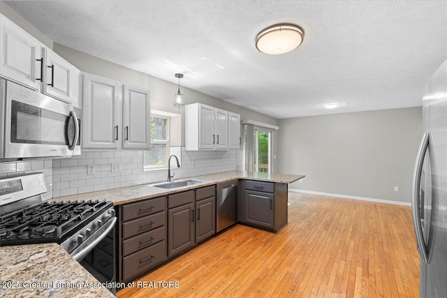 5859 Printemp Dr, East Lansing, MI 48823 - kitchen with stainless steel appliances, a sink, decorative backsplash, a peninsula, and a textured ceiling