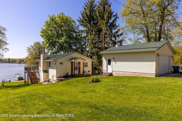 6391 Lakeshore Dr, Lakeview, MI 48850 - rear view of property with entry steps, a yard, a water view, a garage, and metal roof