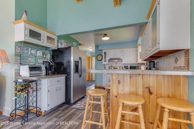 6391 Lakeshore Dr, Lakeview, MI 48850 - kitchen with under cabinet range hood, stainless steel refrigerator with ice dispenser, dark wood-style floors, backsplash, and a peninsula