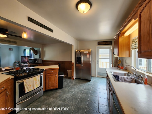 136 N Chestnut St, Owosso, MI 48867 - kitchen with stainless steel appliances, a sink, healthy amount of natural light, brown cabinetry, and a wainscoted wall