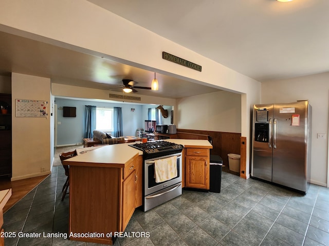 136 N Chestnut St, Owosso, MI 48867 - kitchen with appliances with stainless steel finishes, a wainscoted wall, light countertops, open floor plan, and brown cabinets