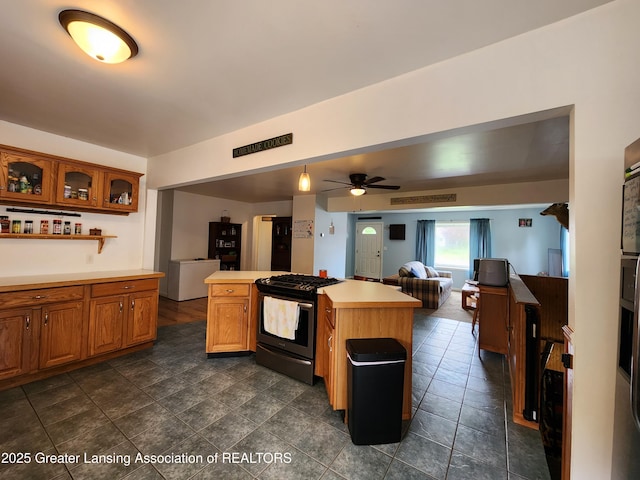 136 N Chestnut St, Owosso, MI 48867 - kitchen featuring stainless steel gas range, open floor plan, light countertops, brown cabinetry, and ceiling fan