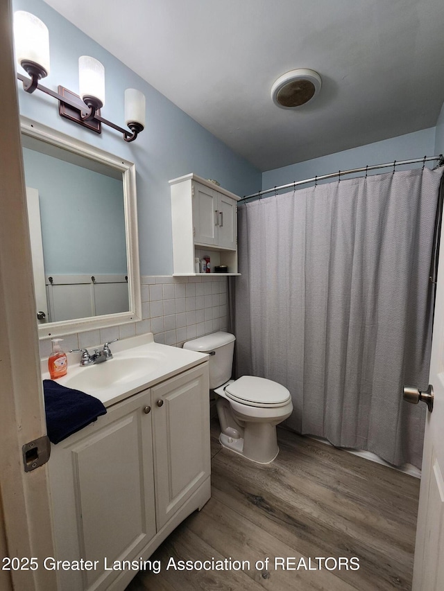 136 N Chestnut St, Owosso, MI 48867 - full bath with wood finished floors, toilet, vanity, backsplash, and a shower with shower curtain