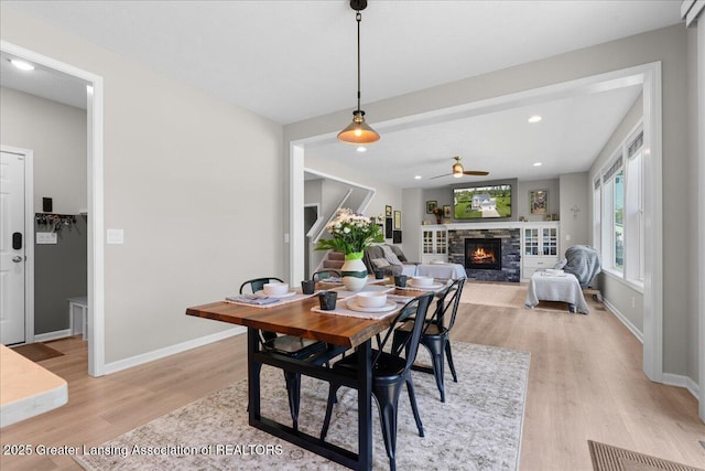 4150 Stillbrook Ln, Dewitt, MI 48820 - dining room featuring a fireplace, light wood-style flooring, a ceiling fan, baseboards, and recessed lighting