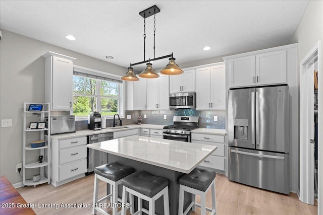 4150 Stillbrook Ln, Dewitt, MI 48820 - kitchen featuring stainless steel appliances, a sink, light wood finished floors, white cabinetry, and backsplash